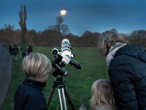 A family is looking through a telescope at the moon